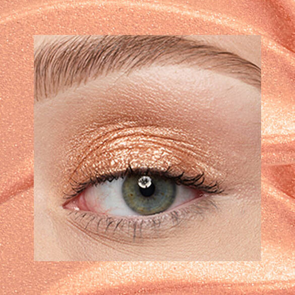 Close-up of an eye area with NYX Professional Makeup Lid Lingerie Cream Eye Pigment in 05 Gold String, shown on a gold shimmer textured background.