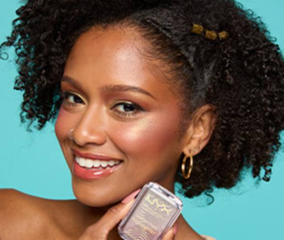 A smiling model with curly hair holds a NYX cosmetics product against a turquoise background, showcasing a vibrant makeup look.